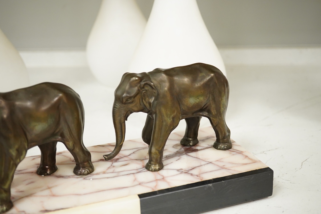 An Art Deco study, three spelter elephants, raised on marble and onyx base, 54cm wide
